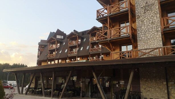 A multi-story wooden building with balconies and a stone facade.