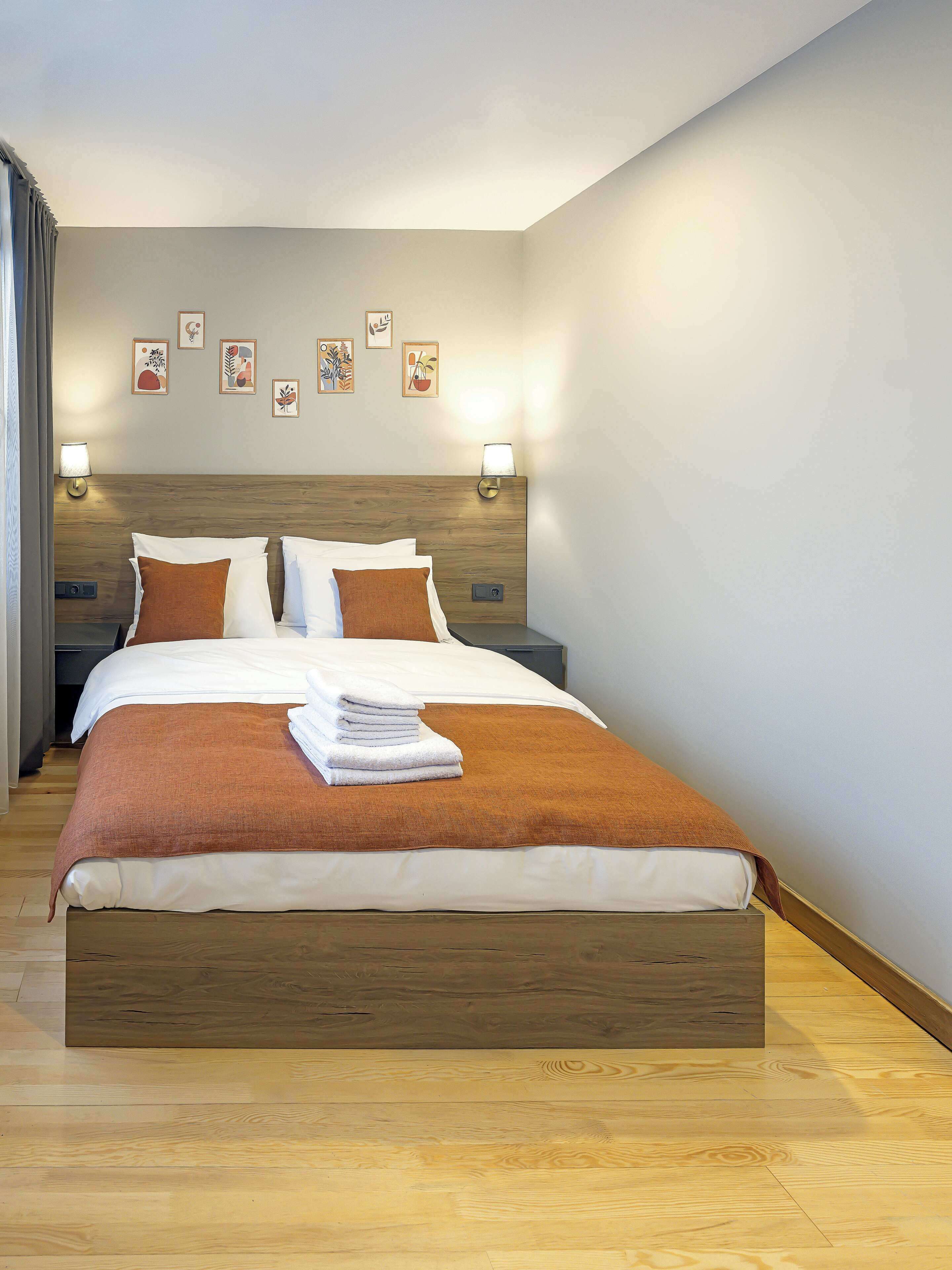 A neatly made bed with a brown headboard, white bedding, and a stack of white towels.