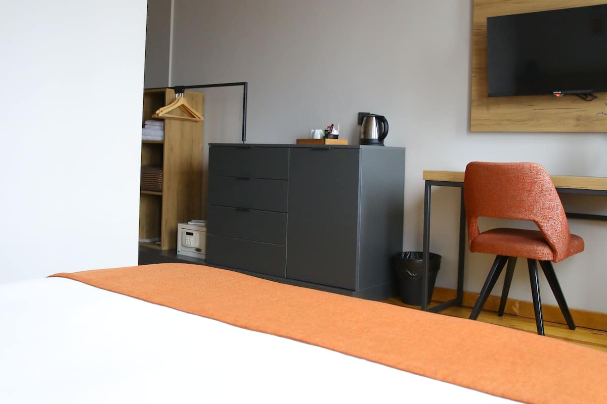 A bedroom with a bed, a desk, a chair, a TV, and a wardrobe.