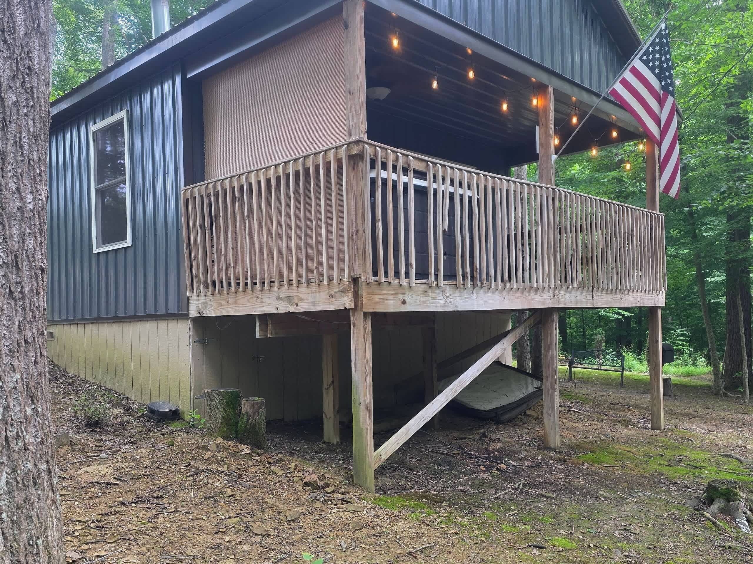 Een blokhut met een houten terras, een klein portaaltje en een Amerikaanse vlag.