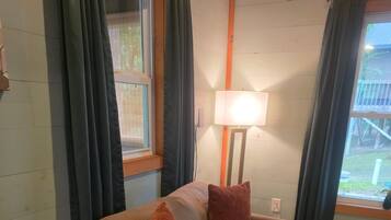 A room with a sofa, a lamp, and a window with curtains.