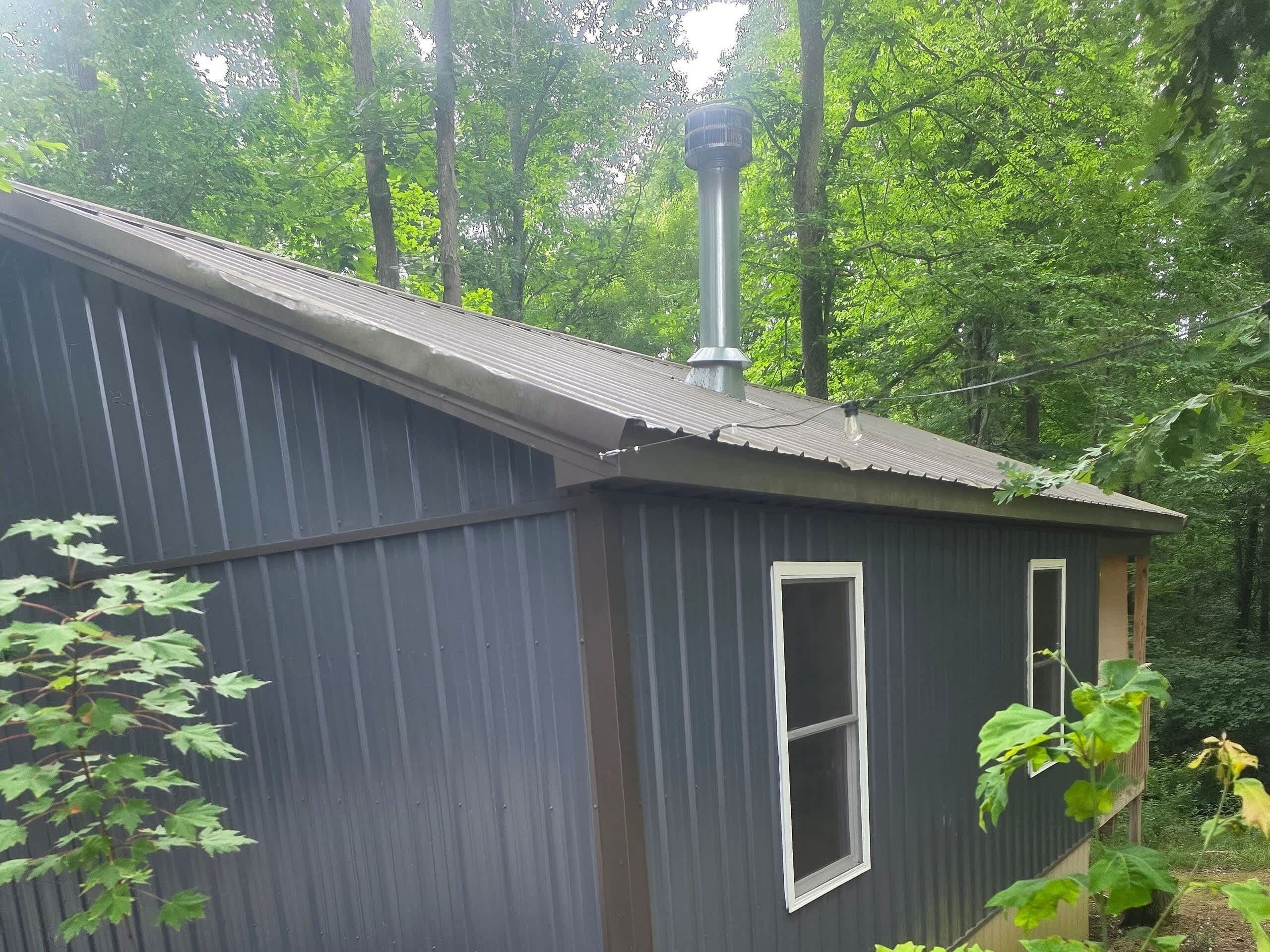 A small, single-story building with a metal roof and a chimney.