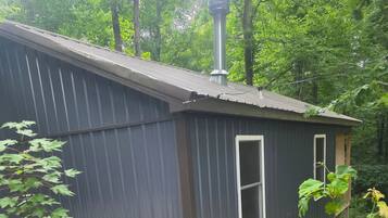 A small, single-story building with a metal roof and a chimney.