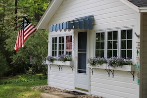 Un bâtiment blanc avec un auvent bleu, une porte et des fenêtres ornées de jardinières.