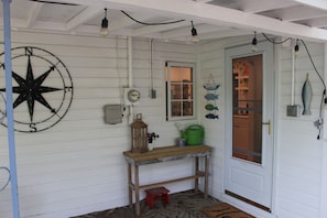 Une pièce avec une table en bois, une décoration murale représentant une boussole, une porte avec une fenêtre et un panneau d’accueil.