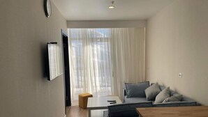 Una sala moderna con un conjunto de sofá, una mesa de centro de madera y un televisor montado en la pared.