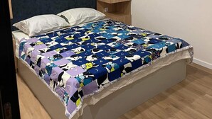 Una cama individual con un edredón colorido, cabecera de madera y armario empotrado de dos puertas.