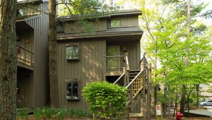 A two-story building with a wooden exterior, a visible fire hydrant, and a staircase leading to the upper floor. - Hawk's Nest 5 (Glen Arbor)