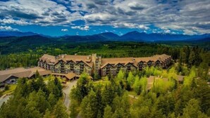 Un albergue con varias construcciones, rodeado de un bosque denso y montañas al fondo.