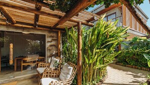 An outdoor seating area with wicker furniture and a bamboo pergola. -  Vila Sal Boutique Noronha (Fernando de Noronha)