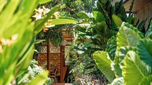 A lush indoor garden with a wooden pathway leading to a seating area. -  Vila Sal Boutique Noronha (Fernando de Noronha)
