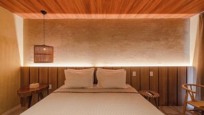 A bedroom with a bed, a hanging light fixture, a wooden headboard, and a small table. -  Vila Sal Boutique Noronha (Fernando de Noronha)