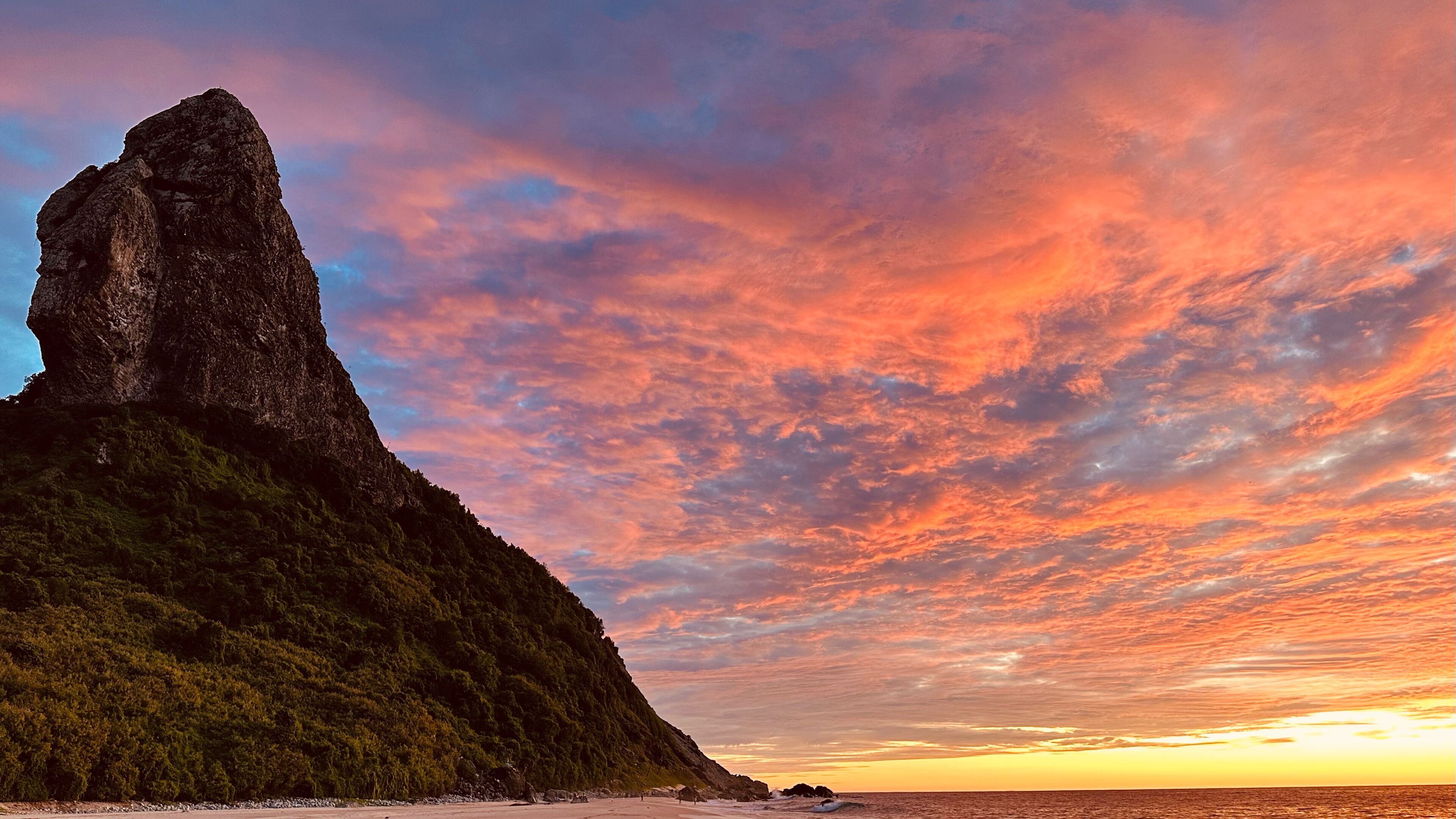 Un paysage côtier caractérisé par une formation rocheuse imposante et une plage.