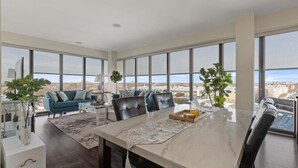 A modern living room with a large dining table, a sofa, and large windows offering a city view. - "Bliss of Evanston" 180°view, 2BDR +2Bath UrbanLux (Evanston)
