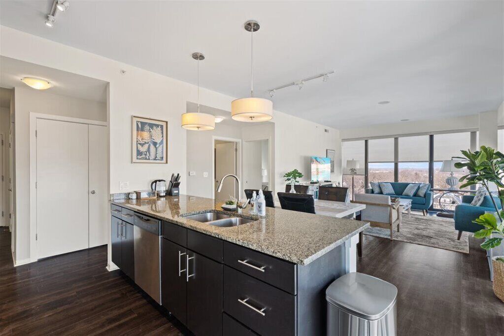 A modern kitchen with granite countertops, stainless steel appliances, and pendant lighting.