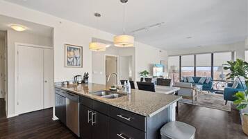 A modern kitchen with granite countertops, stainless steel appliances, and pendant lighting.