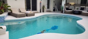 Relax by the curved pool surrounded by lush greenery and comfortable lounge seating.