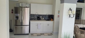 Compact kitchen with stainless steel appliances, white cabinetry, and a black tiled backsplash.
