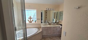Bathroom features a large bathtub, double sink vanity, and a window with a decorative anchor.