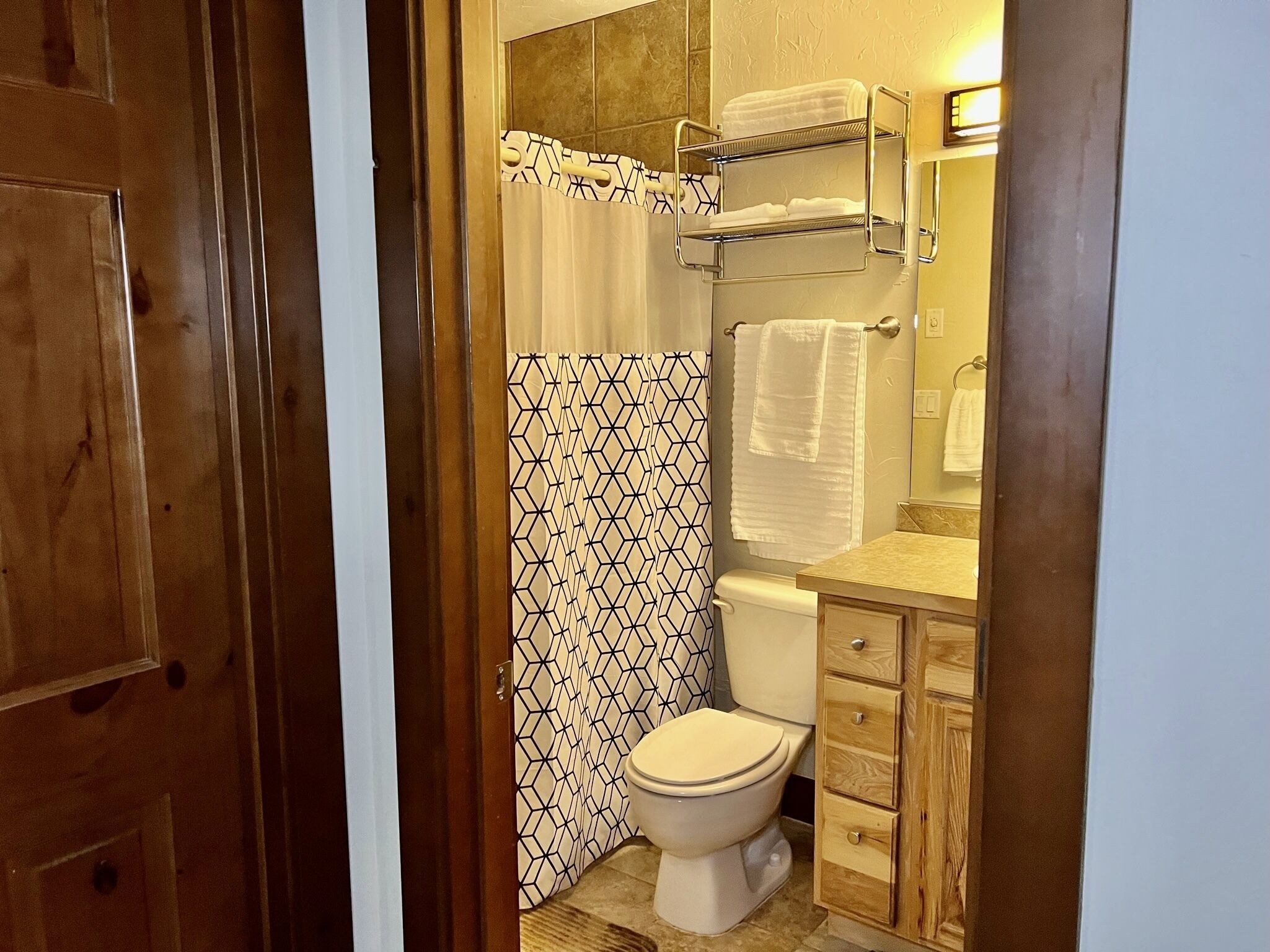 A bathroom with a toilet, a towel rack, and a shower curtain.