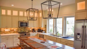A modern kitchen with a central island, stainless steel appliances, and pendant lighting. - Beautiful and pristine 4 bedroom home,  7 minute walk to the Beach! (West Yarmouth)