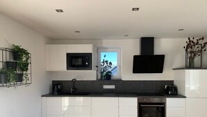 Une cuisine moderne avec des meubles blancs, un plan de travail noir, un four à micro-ondes encastré, une cuisinière et une fenêtre offrant une belle vue.