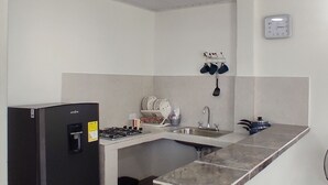 Una cocina compacta con un refrigerador negro, un fregadero, una estufa y un reloj en la pared.
