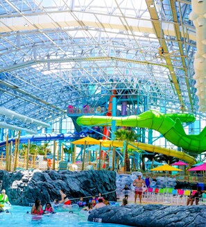 An indoor water park with a large glass ceiling, multiple water slides, and a pool area.