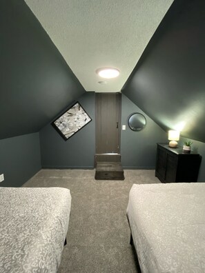A bedroom with two beds, a small staircase, a wall-mounted mirror, and a nightstand with a lamp. - Small private home walking distance to Suny Potsdam/Clarkson!  (Potsdam)