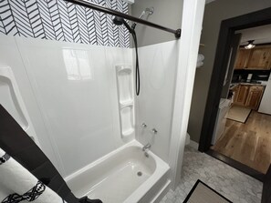 A modern bathroom with a bathtub, shower, and a herringbone-patterned wall. - Small private home walking distance to Suny Potsdam/Clarkson!  (Potsdam)