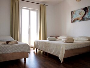 Two single beds with matching headboards and footboards, a large window with a sliding glass door, and a simple, functional design.