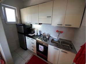 Compact kitchen with a modern design, featuring a refrigerator, stove, and sink.