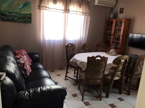Relax in this inviting living room with a comfortable sofa, dining table, and large window.