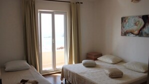 Une chambre d’hôtel avec deux lits, une porte-fenêtre coulissante donnant sur la plage et un tableau au mur.