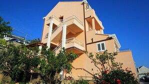 A multi-story building with balconies, a satellite dish, and a clear blue sky.