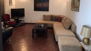 A living room with a sofa, a coffee table, a TV, and a red chair.