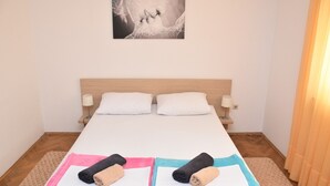 A single bed with two pillows, a bedside table with a lamp, and a wall-mounted picture.