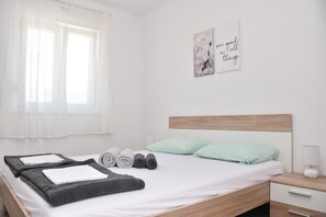 A neatly made bed with pillows, a bedside table with a lamp, and a wall with a motivational quote.