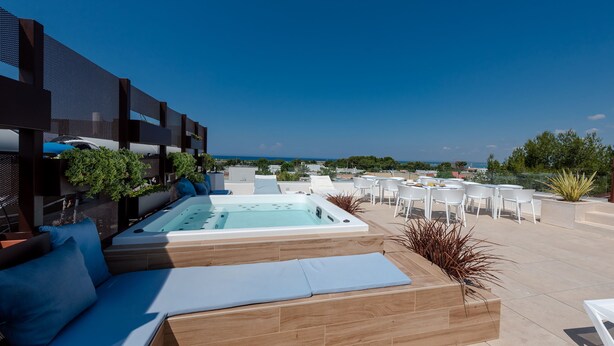 Una terraza en la azotea con jacuzzi, sillones de relax y mobiliario exterior.