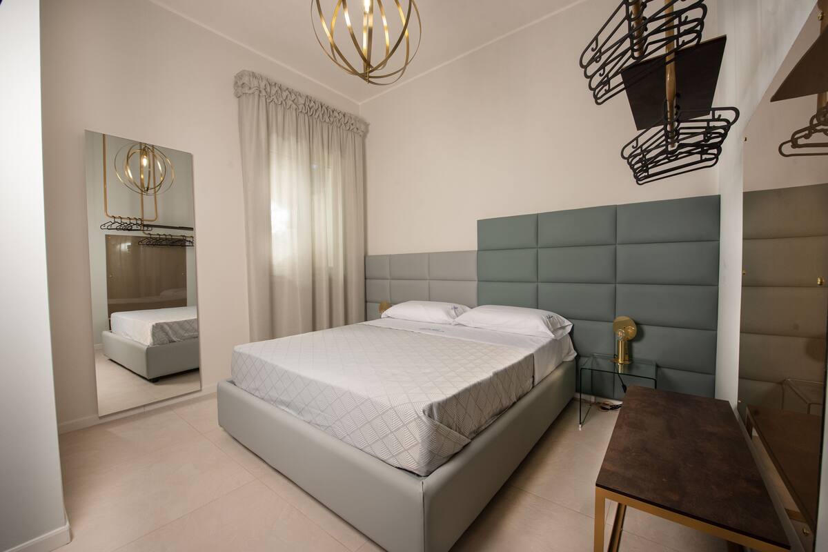 Un dormitorio moderno con una cama grande, una mesita de noche, un espejo y una lámpara de diseño único.