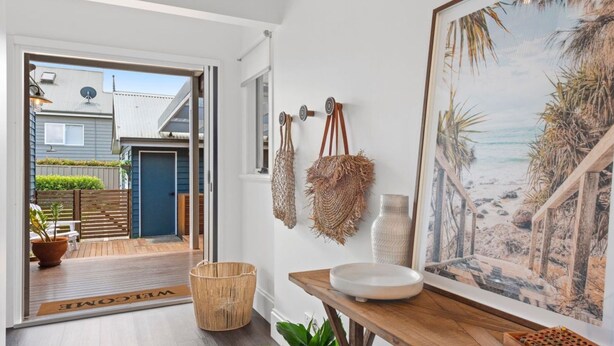 A modern interior with a wooden bench, a white basin, and a beach-themed painting.