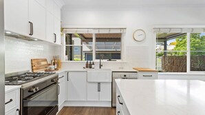 A modern kitchen with white cabinetry, a large island, a built-in oven, and a window with a view of the outdoors.