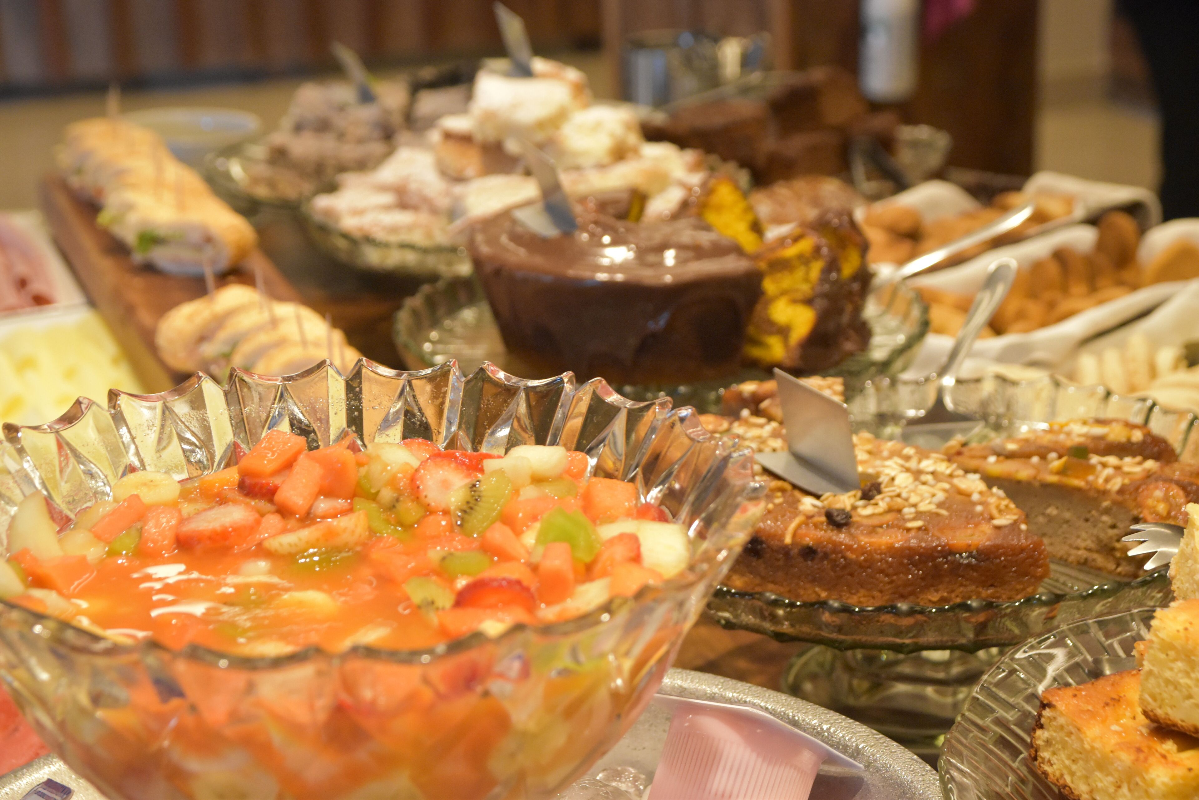 A buffet with various dishes including a fruit salad, chocolate dessert, and other assorted foods.
