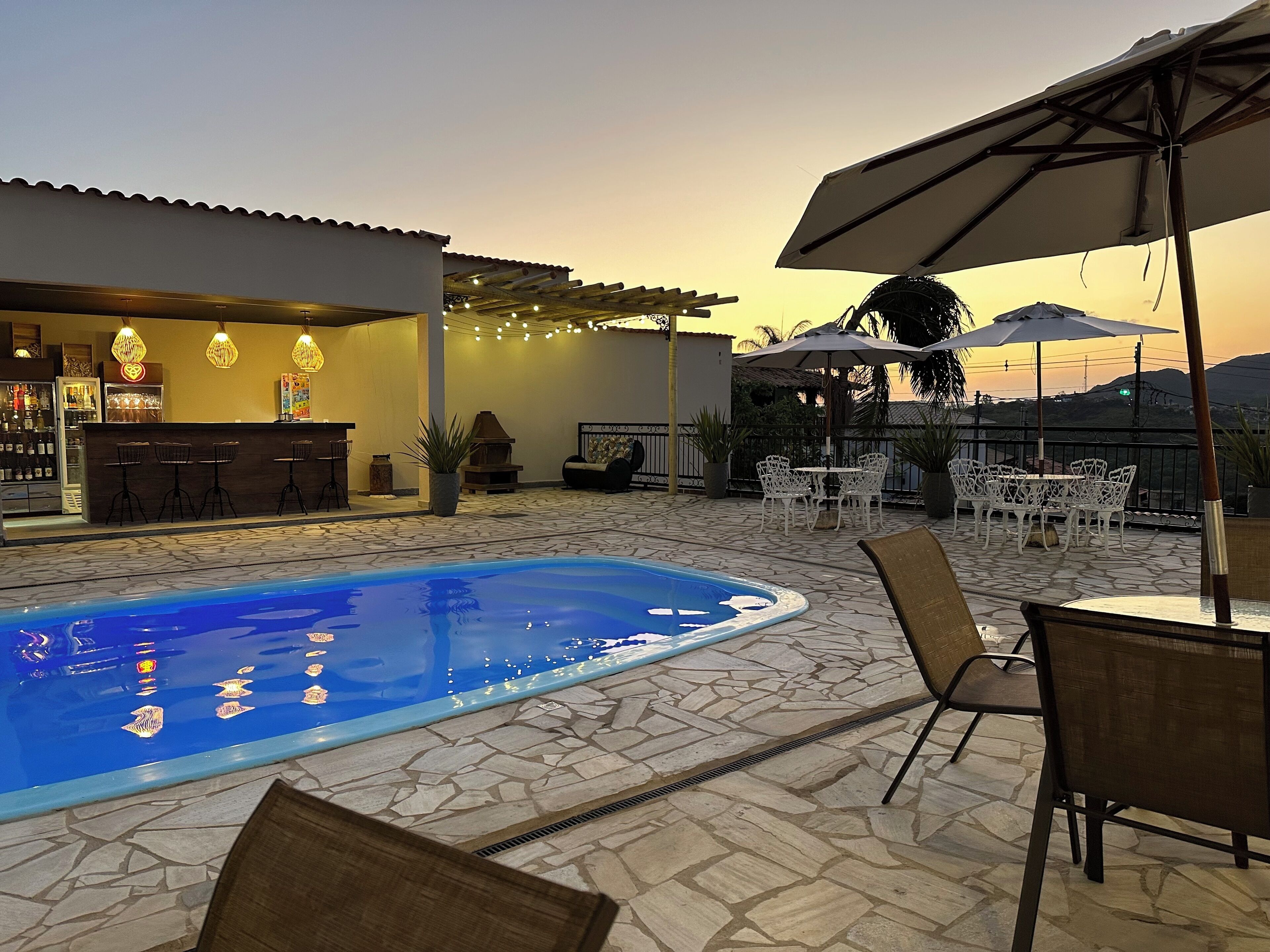 An outdoor pool area with a bar, seating, and umbrellas.