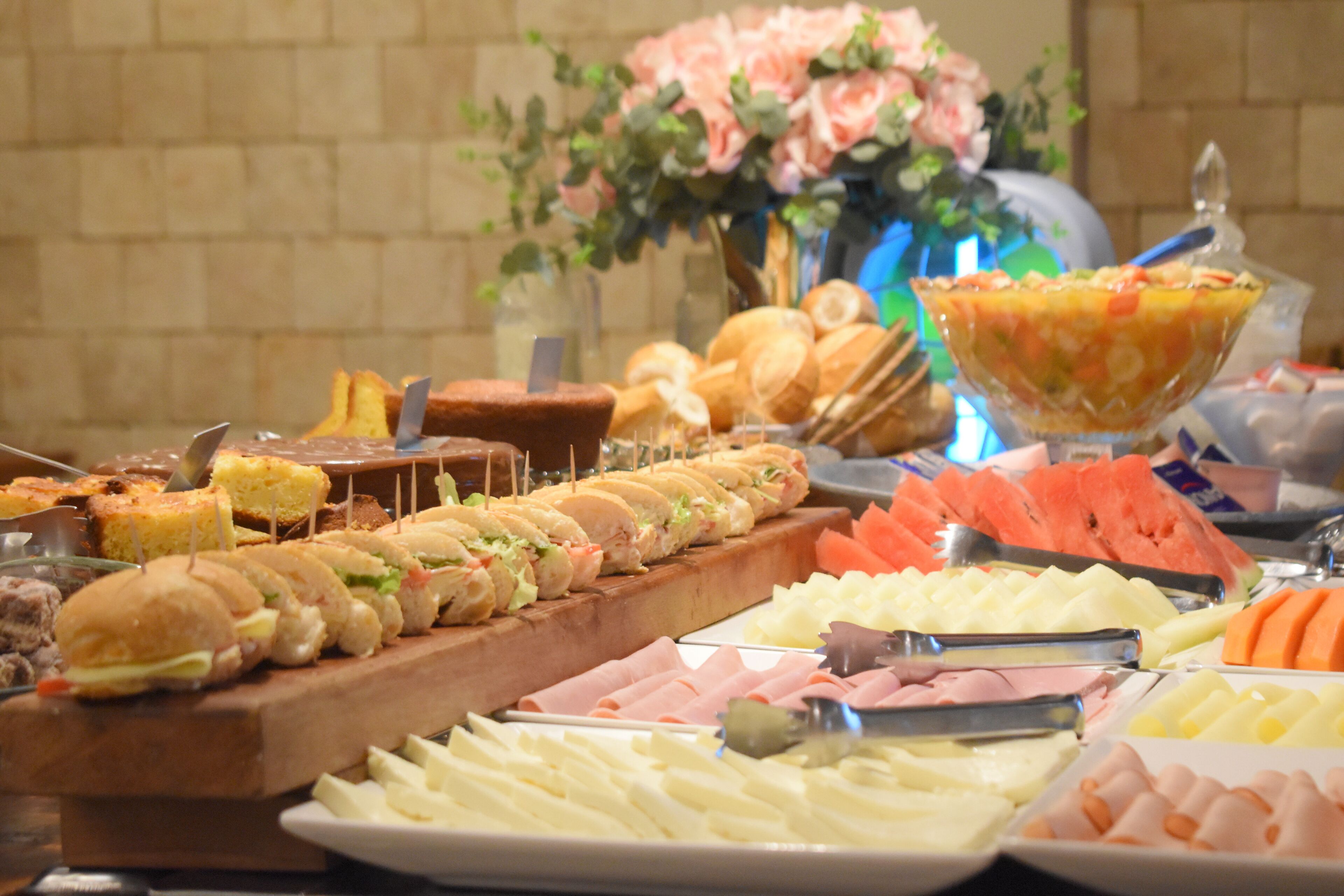 A buffet with various food items including sandwiches, fruits, and cheeses.