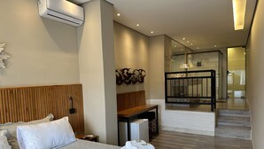 Una habitación de hotel moderna con una cama grande, un cabecero de madera, un escritorio y un balcón con cerramiento de vidrio.