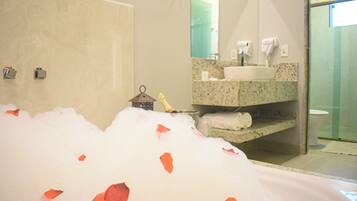 A bathroom with a bathtub filled with bubbles and rose petals, a sink, and a toilet.