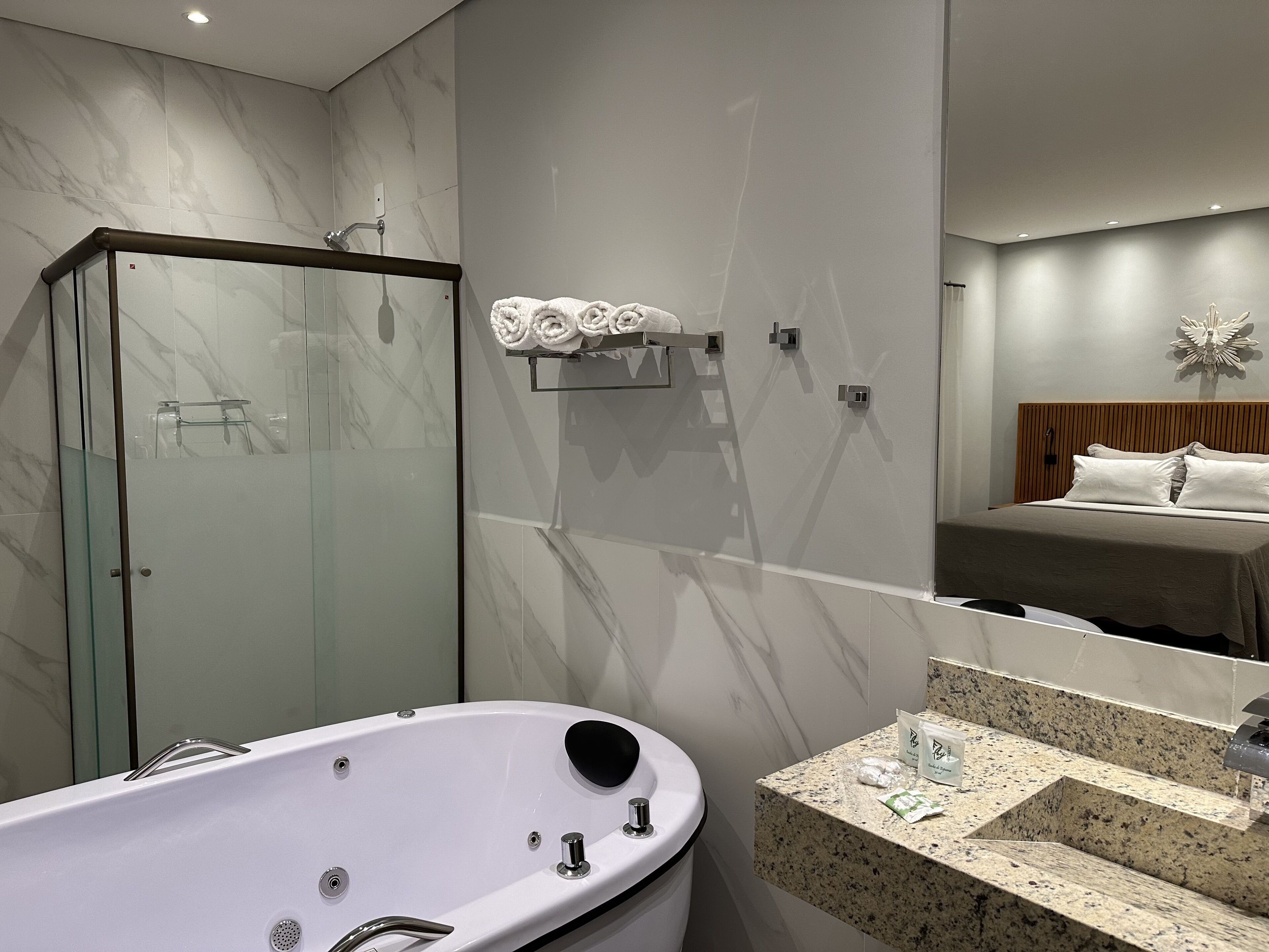 Ein modernes Badezimmer mit einer gläsernen Duschkabine, einer freistehenden Badewanne und einem Waschtisch mit einer Granitplatte.