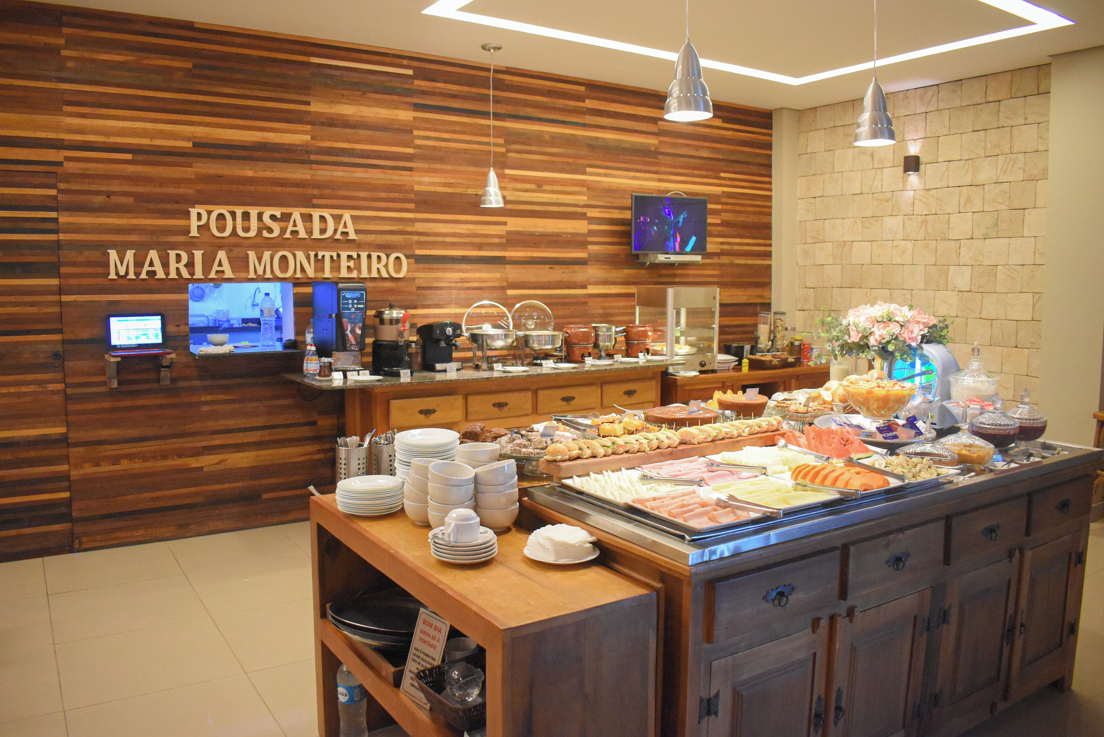 A buffet area with a wooden wall, a TV screen, and various food items displayed.