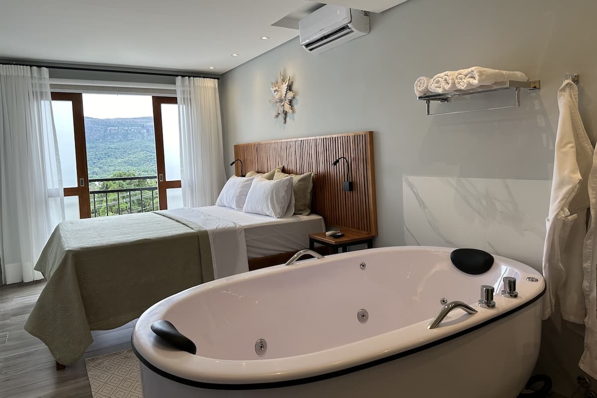 Quarto de hotel com cama, uma banheira grande e vista para o exterior.